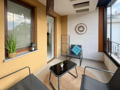 a balcony with two chairs and a table and windows at SOS CoMFORT 2 LAZUR in Burgas City