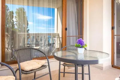 a glass table with chairs and a vase of flowers on a balcony at Casa de la playa in Varna City