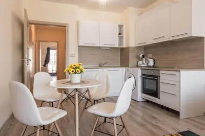 a kitchen with white cabinets and a table and chairs at Casa de la playa in Varna City