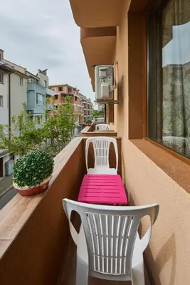 a balcony with a pink table and chairs on a balcony at Hotel Niko's in Pomorie