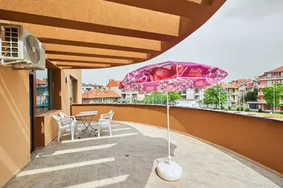 a pink umbrella on a balcony with a table and chairs at Hotel Niko's in Pomorie