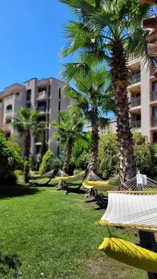 a row of hammocks in a park with palm trees at Deluxe Appartements in Cascadas Family Resort Sunny Beach in Sunny Beach