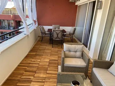 a balcony with chairs and a table and windows at SEAVIEW Heaven Sunny Beach in Sunny Beach