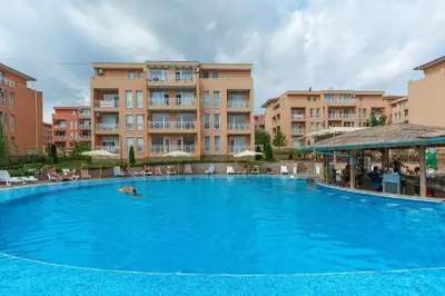 a large blue swimming pool in front of some buildings at Ground Floor, Studio Apartment at Sunny Day 6 in Tŭnkovo