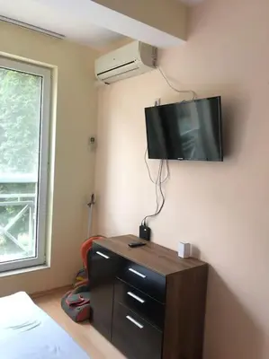 a bedroom with a tv on the wall and a dresser at Ground Floor, Studio Apartment at Sunny Day 6 in Tŭnkovo
