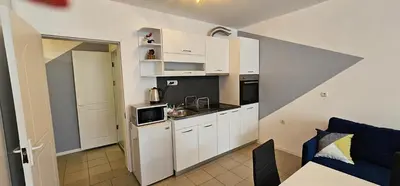 a small kitchen with white cabinets and a blue couch at Studio Nina in Primorsko