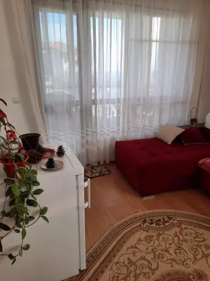 a living room with a red couch in front of a window at Прекрасный апартамент с видом на море и бассейном in Byala