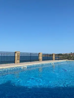 a swimming pool with blue water in front of a fence at SH Holidays & Health Beach-Apartments in Sozopol