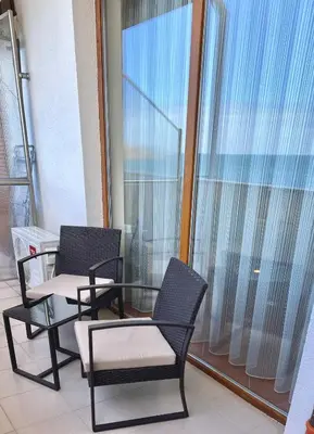 two chairs and a glass table on a balcony at SH Holidays & Health Beach-Apartments in Sozopol