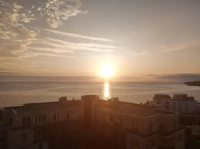 a sunset over the ocean with a building in the foreground at The View Apartment in Sozopol