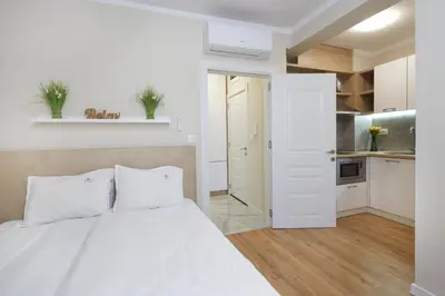 a white bedroom with a bed and a kitchen at Bellicity Apart Complex in Ravda
