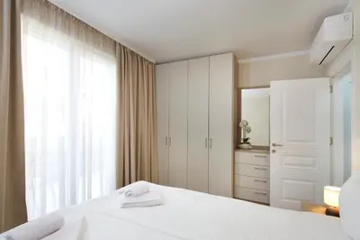 a bedroom with a white bed and a large window at Bellicity Apart Complex in Ravda