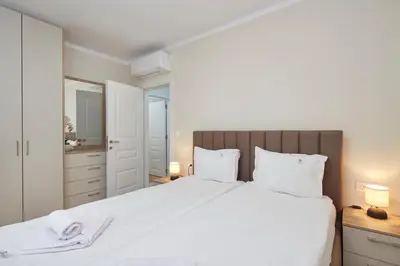 a bedroom with a large white bed with two lamps at Bellicity Apart Complex in Ravda
