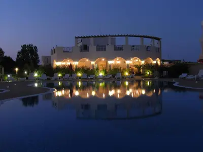 a building with lights in front of a pool at night at Hotel Paradise Garden in Chernomorets