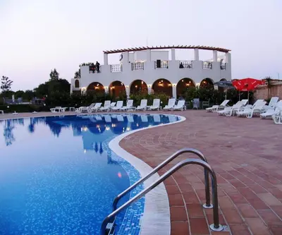 a swimming pool with chairs and a building at Hotel Paradise Garden in Chernomorets