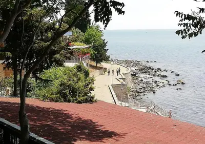people walking on a sidewalk next to the water at Kims One-bed Apart for rent at Sunny Beach Resort in Sunny Beach