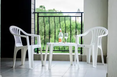 two white chairs and a table with wine glasses on a balcony at Cantilena Complex in Sunny Beach