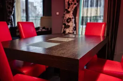 a wooden table with red chairs around it at Aпартамент в близост до морето и центъра in Burgas City