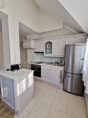 a kitchen with white cabinets and a stainless steel refrigerator at Център Варна апартамент с паркинг за нормална до средно голяма кола in Varna City