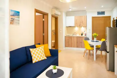 a living room with a blue couch and a kitchen at Cozy Home Santa Marina Sozopol in Sozopol