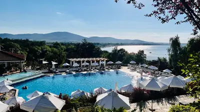 a large swimming pool with umbrellas and a lake at Cozy Home Santa Marina Sozopol in Sozopol
