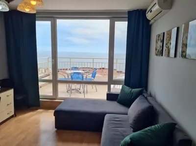 a living room with a couch and a view of a balcony at Imperial Fort Club Apartament in Sveti Vlas