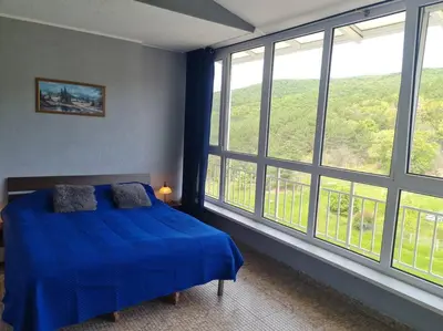a bedroom with a blue bed and large windows at Imperial Fort Club Apartament in Sveti Vlas