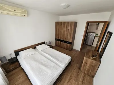a bedroom with a white bed and a refrigerator at Apartment Fort Noks in Sveti Vlas