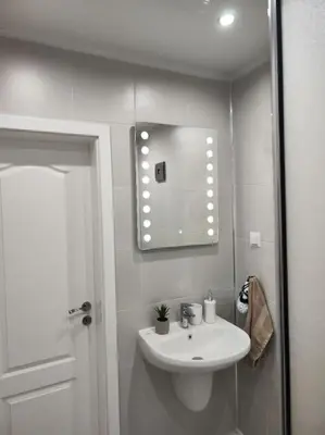 a white bathroom with a sink and a mirror at Sea apartment Lazur - next to the beach in Burgas City