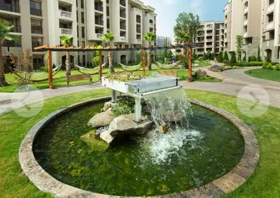 a fountain in the middle of a park with a bench at Dream Cascadas - Слънчев бряг in Sunny Beach