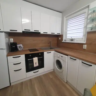 a kitchen with white cabinets and a washing machine at Apartment Voivoda in Varna City