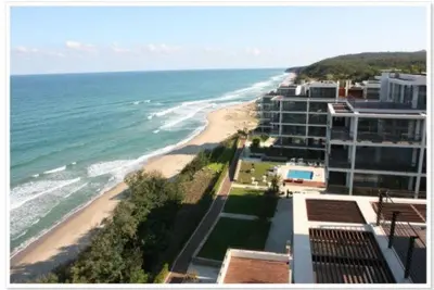 a view of a beach with a building and the ocean at Private Apartments in Yoo Bulgaria Complex in Obzor