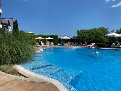 a person swimming in a large blue swimming pool at ROYAL BAY 6 Sea View Apartment in Sveti Vlas