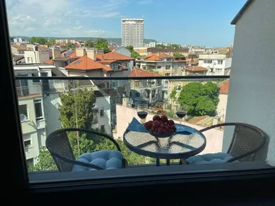 a table with a bowl of fruit and wine glasses on a balcony at Panoramic apartment in Varna with underground parking in Varna City