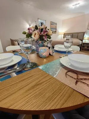a wooden table with plates and wine glasses on it at Нощувки Свети Влас Комплекс Амфора , студио 704 in Sveti Vlas