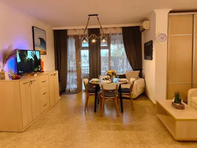 a living room with a table and a dining room at Нощувки Свети Влас Комплекс Амфора , студио 704 in Sveti Vlas