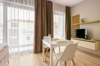 a room with a white table and chairs and a television at Open Sea Panorama Residence in Obzor
