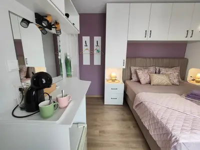 a bedroom with a bed with purple walls and white cabinets at AMORE Obzor in Obzor