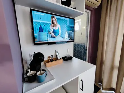a room with a television on a wall with a white desk at AMORE Obzor in Obzor