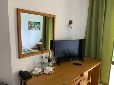 a television on a wooden table with a mirror at Хотел ЗОНАРИТА in Primorsko