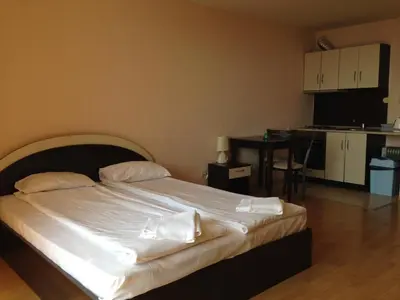 a bedroom with a bed with white sheets and a kitchen at Apartments in Panorama Beach Vigo Nessebar in Nesebar