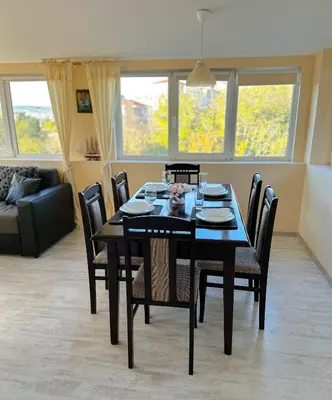 a dining room with a black table and chairs at Апартамент Joy in Varna City