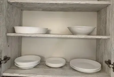 three bowls and plates on shelves in a kitchen at Апартамент Joy in Varna City