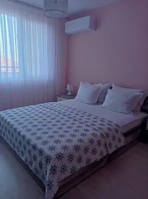 a bedroom with a bed with a blue and white comforter at Apartament Lili Sozopol in Sozopol