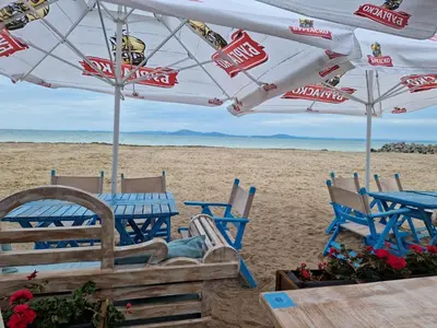 a beach with chairs and an umbrella on the beach at Sarafovo Resort Deluxe in Burgas City