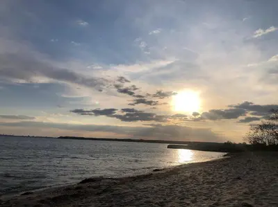 a sunset on a beach with the sun in the sky at Pomorie Direkt am Pool in Pomorie