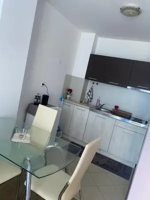 a kitchen with a glass table and white cabinets at Pomorie Direkt am Pool in Pomorie