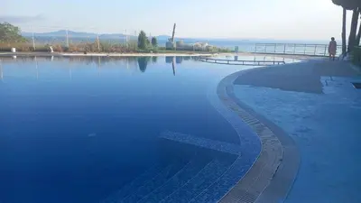 a pool of water with a person standing next to it at Pomorie Direkt am Pool in Pomorie