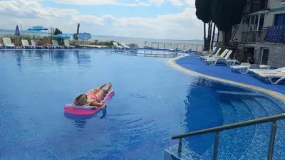 a young girl riding on a raft in a swimming pool at Pomorie Direkt am Pool in Pomorie