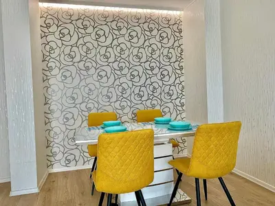 a dining room table with yellow chairs and a wall at AVRORA in Varna City